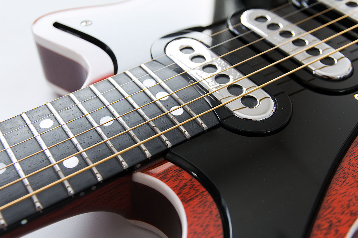 Red Special Custom. Nachbau von Brian May's E-Gitarre aus Mahagonie, transparent rot lackiert. Detailansicht der polierten Edelstahlbünde im schwarzen Ebenholz Griffbrett.