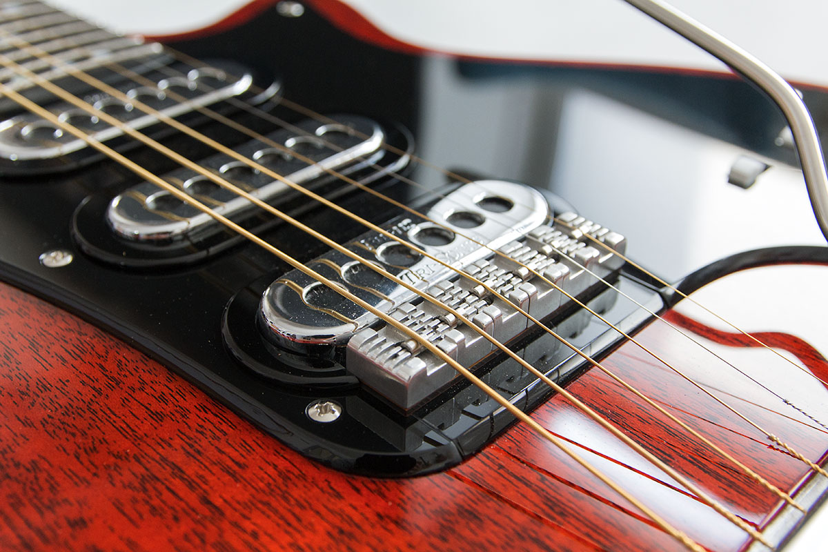 Red Special Custom. Nachbau von Brian May's E-Gitarre aus Mahagonie, transparent rot glänzend lackiert. Detailansicht der Rollerbridge und den Pickups mit Chromcover.