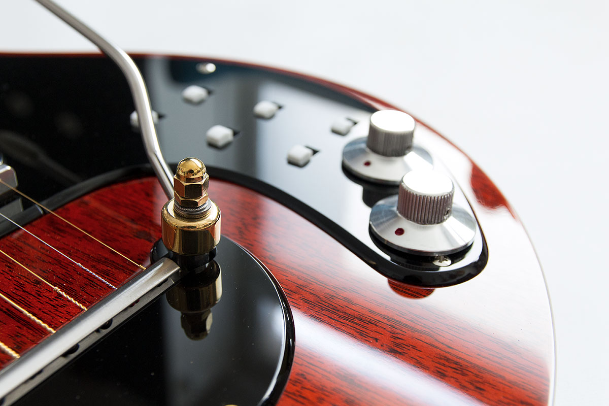 Red Special Custom. Nachbau von Brian May's E-Gitarre aus Mahagonie, transparent rot. Detail des Tremolohebels aus Chrom und Messing.